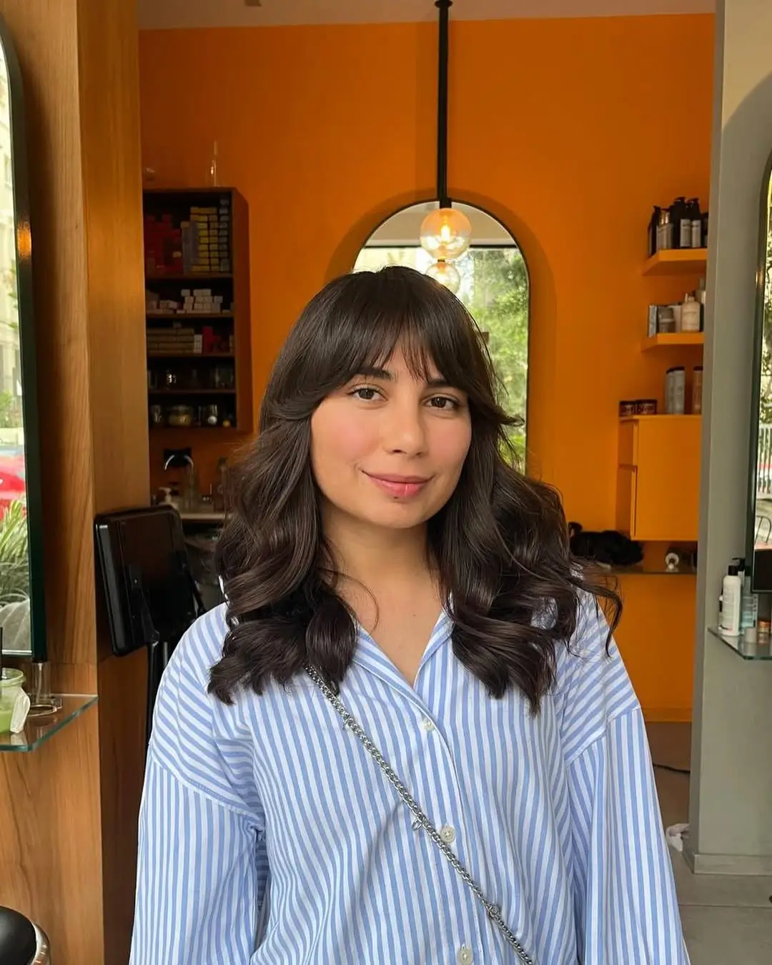 layered summer haircut for round face 2026 Mid Length Curly Layers with Soft Bangs