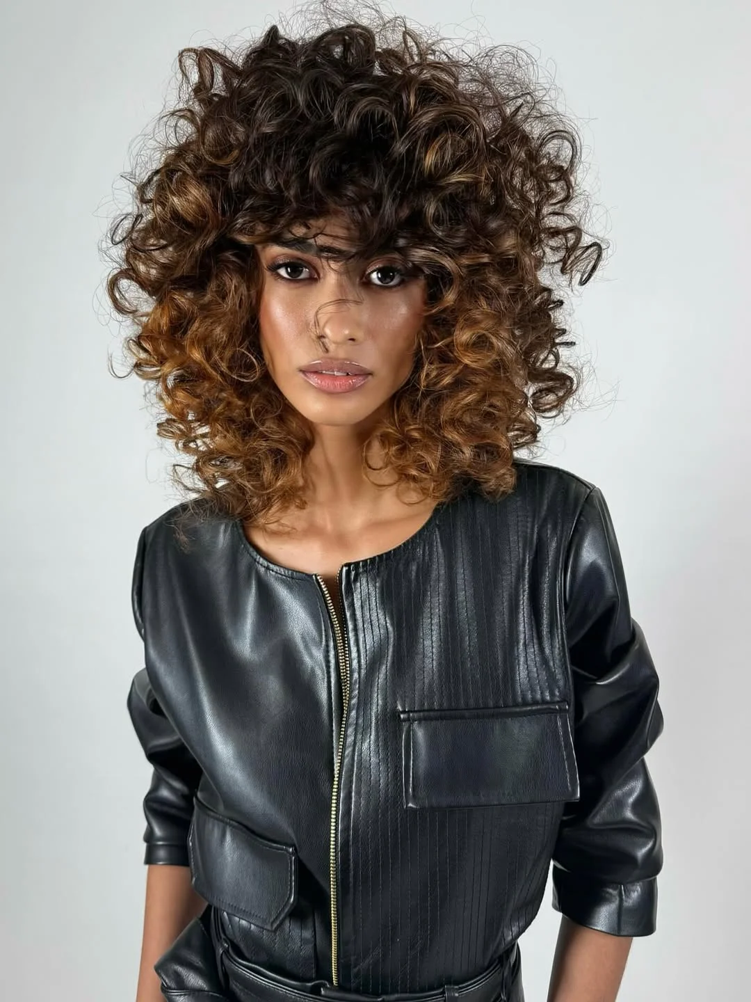 warm summer hair color for tan skin 2026 Deep Brunette Curls with Caramel Highlights