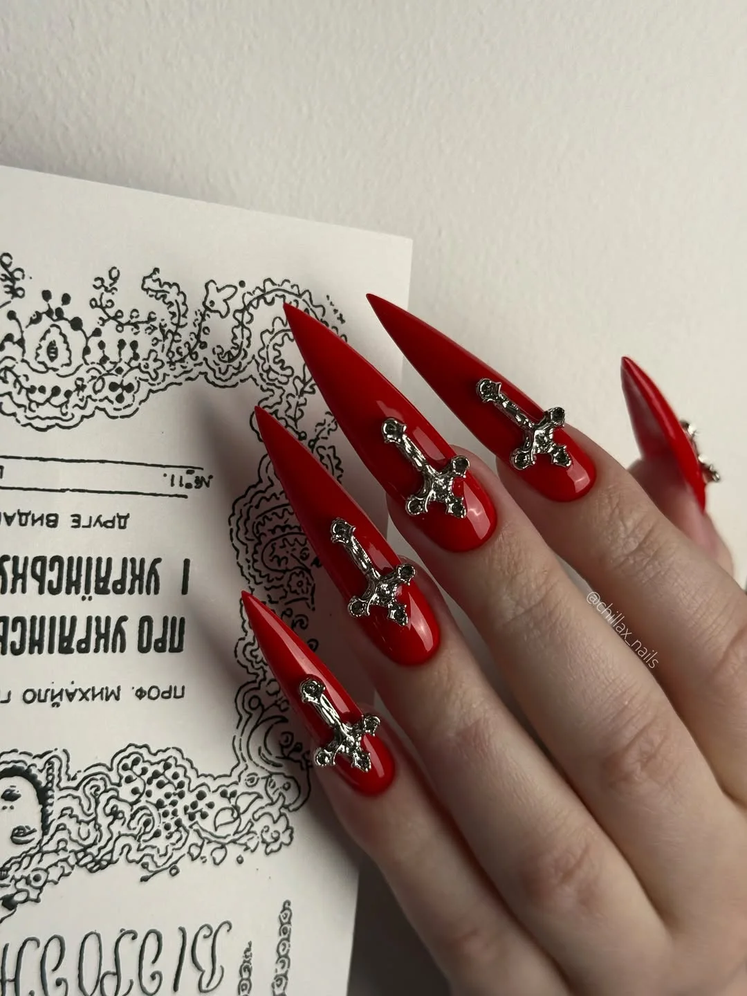 pretty july nails design ideas 2026 Bold Scarlet Stiletto Nails with Gothic Silver Charms