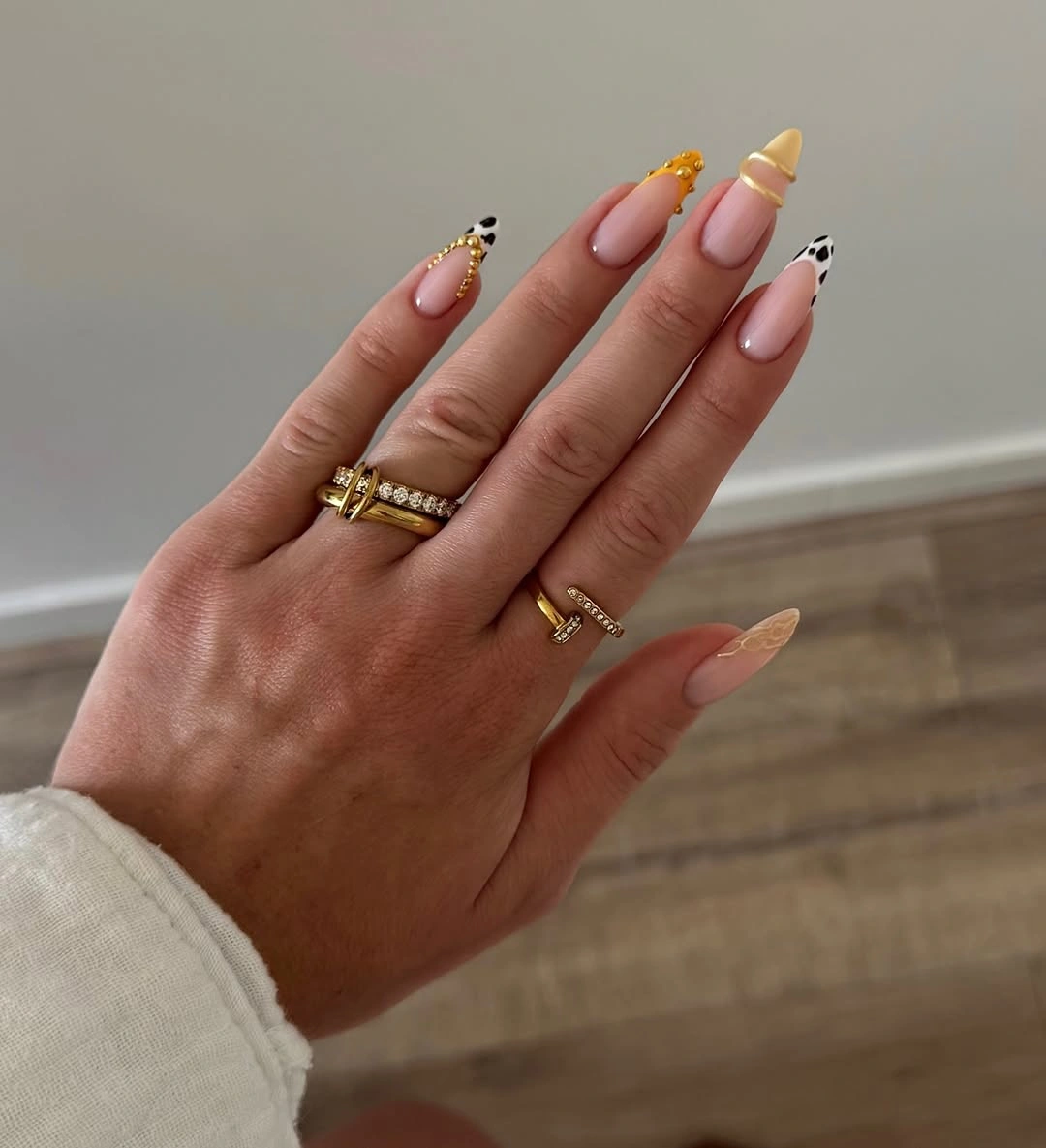 chic fall trendy nails 2026 Soft Nude Almonds With Cow Print and Gold Jewelry Details