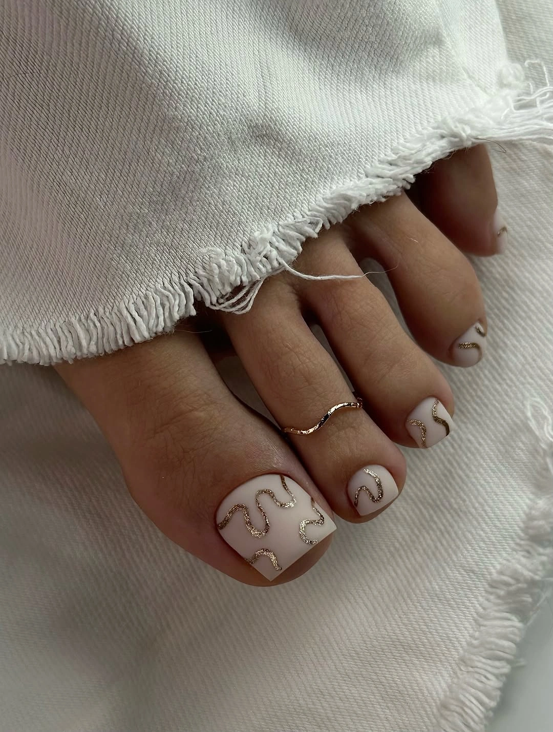 stylish fall toe nails colors 2026 - Ivory Pedicure With Delicate Gold Waves